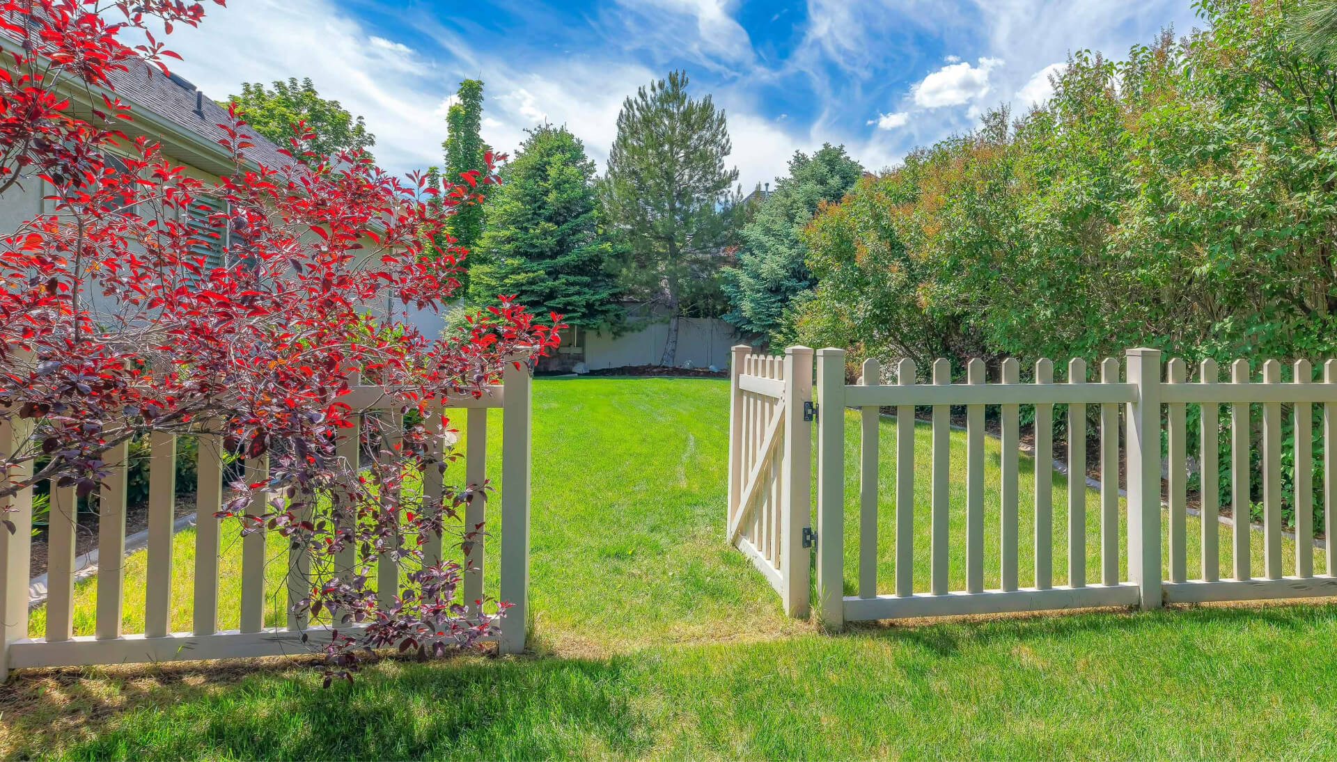 A functional fence gate providing access to a well-maintained backyard, surrounded by a wooden fence in Hampton